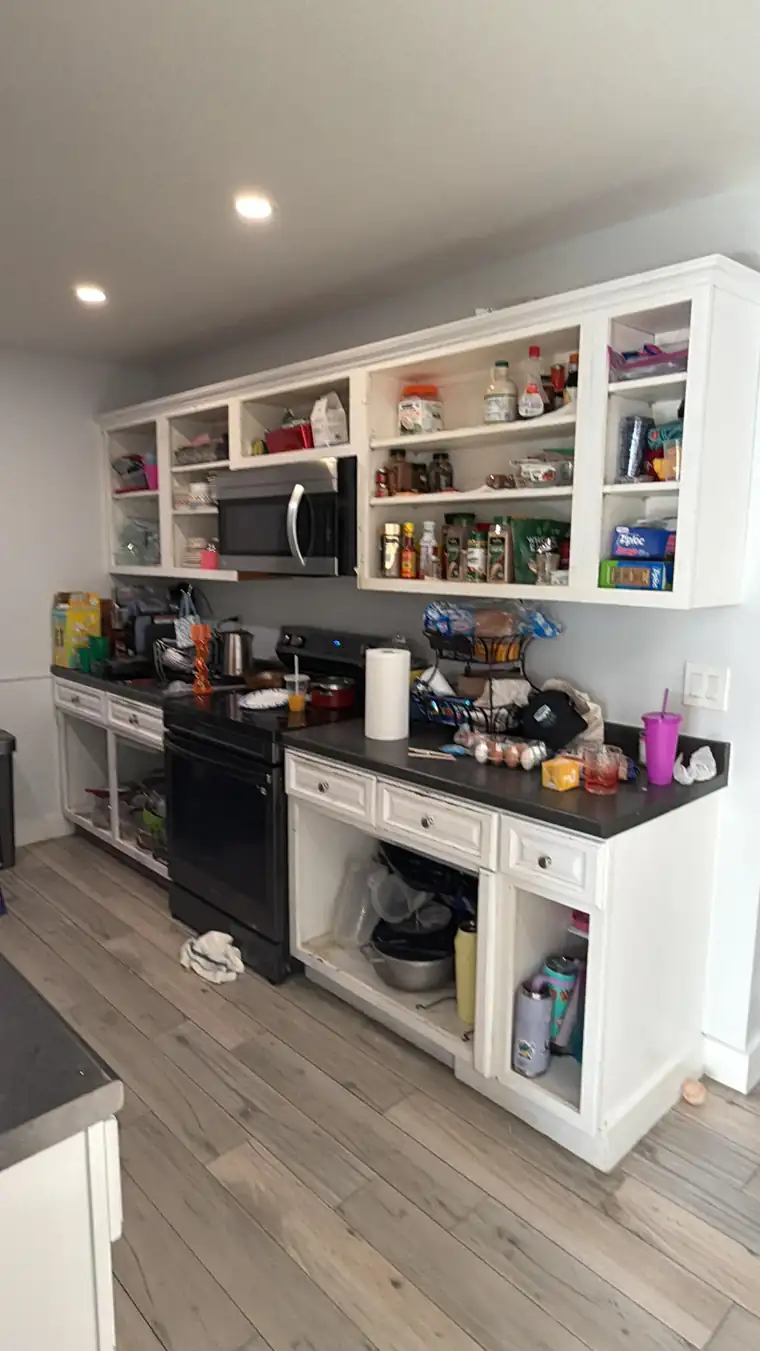 Before: the same kitchen with open shelving, a black range and worn counters