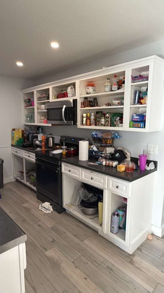 Before: the same kitchen with doorless cabinets, black countertops and cluttered shelves
