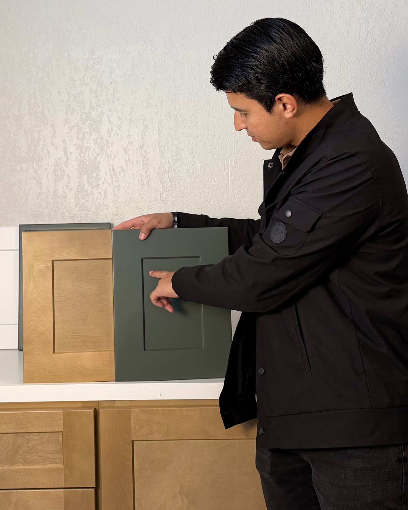 Daniel, co-founder of D’Panim Remodeling, holding a green shaker cabinet door sample