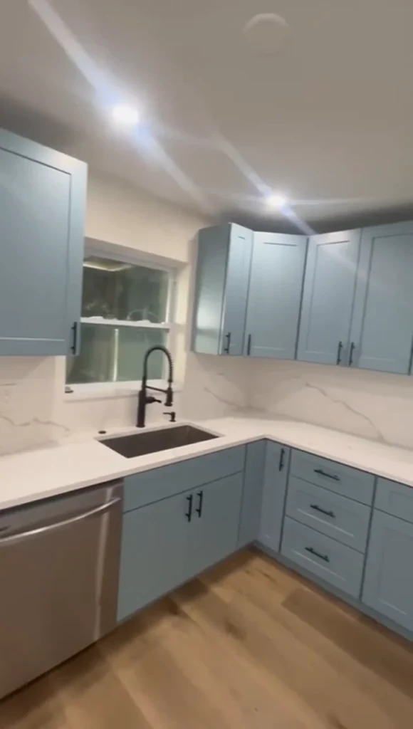 Sage-blue shaker kitchen with black faucet