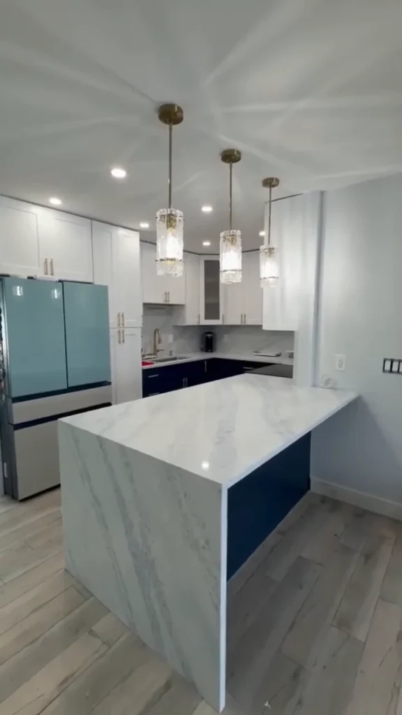 Two-tone kitchen with waterfall island and crystal pendants